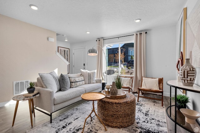 living room with a textured ceiling, recessed lighting, baseboards, wood finished floors, and visible vents