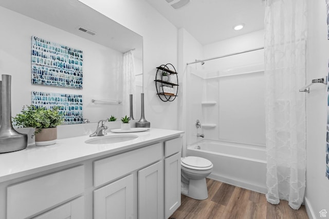bathroom featuring shower / bath combination with curtain, visible vents, wood finished floors, vanity, and toilet