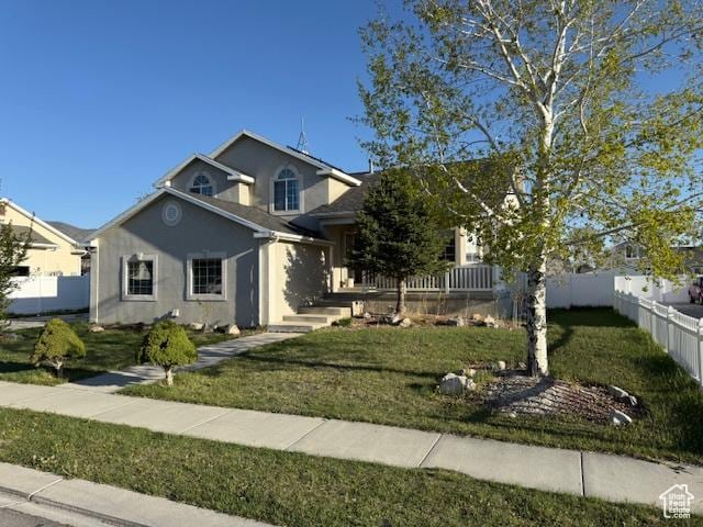 view of front of property featuring fence, a front lawn, and stucco siding