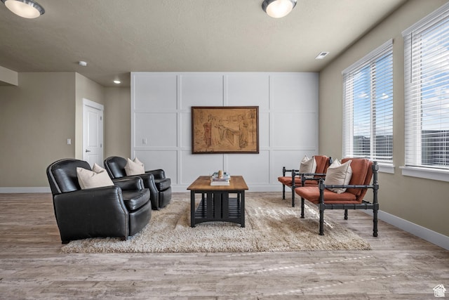 living area with baseboards, a textured ceiling, and wood finished floors