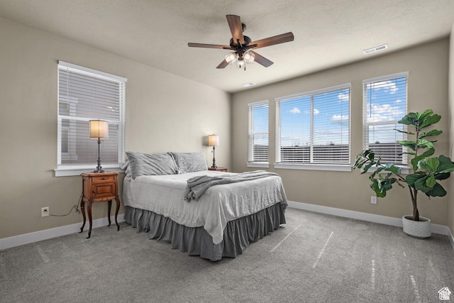 carpeted bedroom with baseboards, a ceiling fan, and visible vents