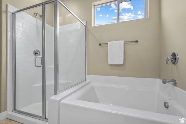 full bath featuring a healthy amount of sunlight, a stall shower, and a garden tub