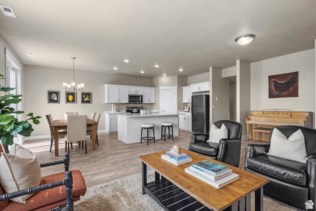 living area featuring an inviting chandelier, light wood-style flooring, recessed lighting, baseboards, and visible vents