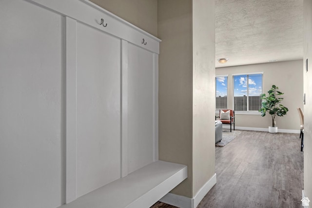 mudroom featuring baseboards, a textured ceiling, and wood finished floors