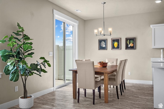 dining area featuring baseboards, an inviting chandelier, and wood finished floors