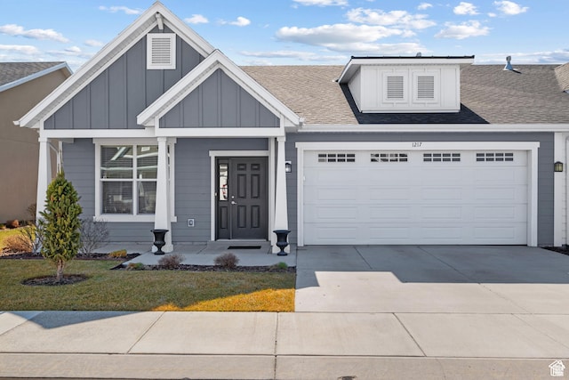 view of front of property featuring board and batten siding, a front yard, concrete driveway, an attached garage, and a shingled roof