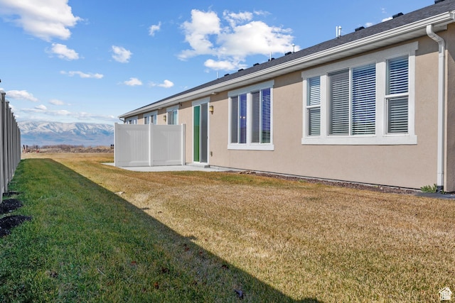 back of property featuring a lawn, stucco siding, and fence