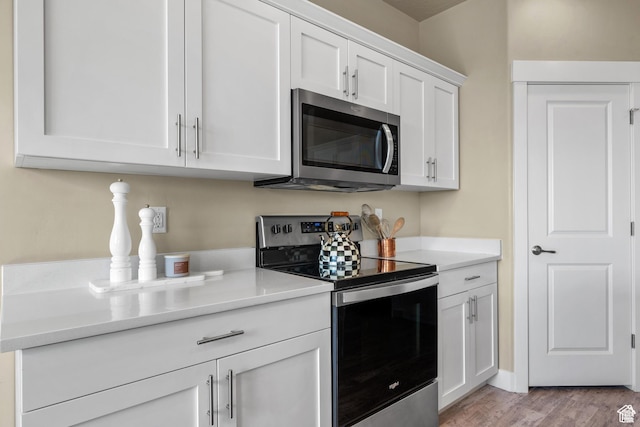 kitchen with light countertops, stainless steel appliances, light wood-type flooring, and white cabinetry