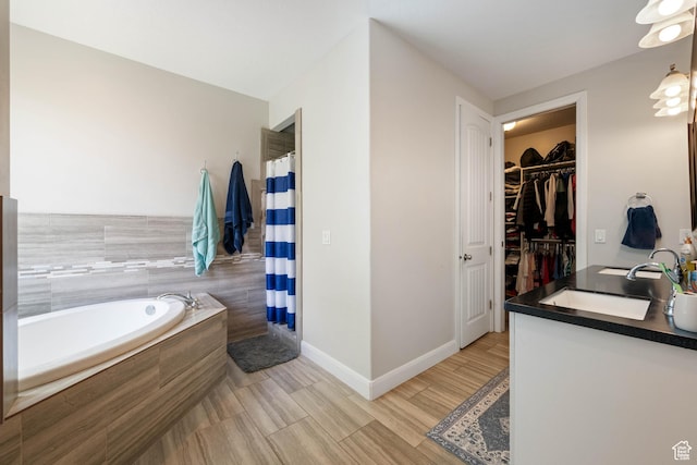 bathroom with a walk in closet, a sink, a shower with shower curtain, baseboards, and a bath