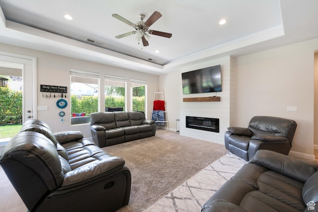 living room featuring ceiling fan, a fireplace, recessed lighting, a tray ceiling, and visible vents