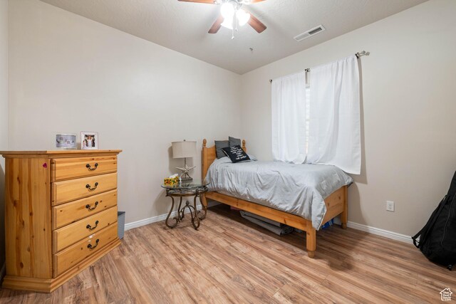 bedroom featuring baseboards, ceiling fan, light wood-style flooring, and visible vents