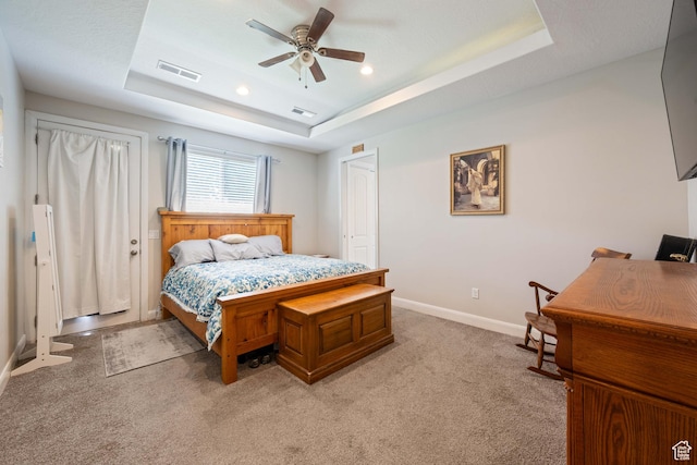 bedroom featuring baseboards, visible vents, light carpet, and a raised ceiling