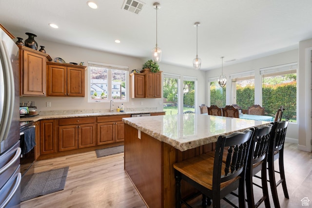 kitchen featuring a sink, a center island, brown cabinets, and visible vents