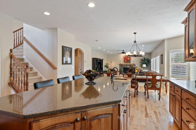 kitchen with light wood-style flooring, a sink, a fireplace, open floor plan, and recessed lighting