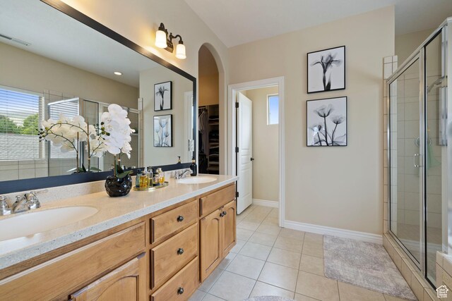 bathroom featuring a stall shower, tile patterned flooring, a sink, and a walk in closet