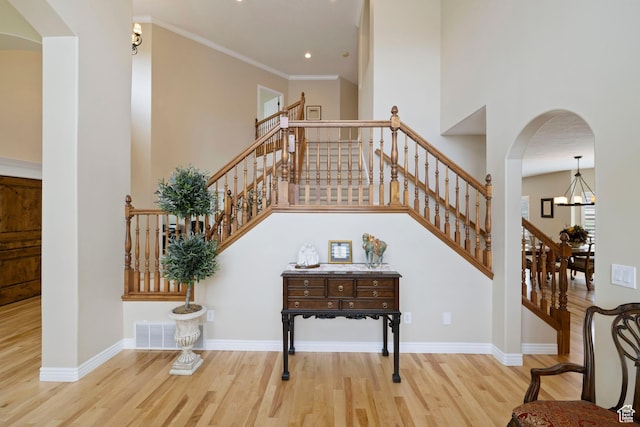 staircase featuring a notable chandelier, baseboards, visible vents, wood finished floors, and arched walkways