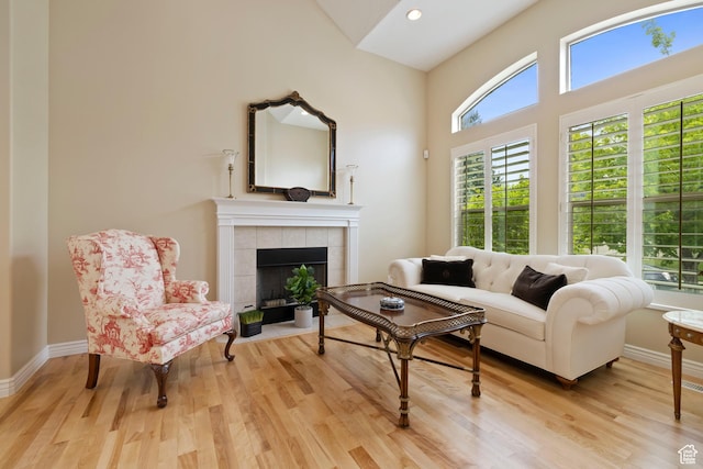 living room featuring a tile fireplace, a healthy amount of sunlight, and wood finished floors