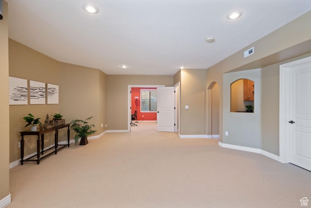 interior space with recessed lighting, baseboards, visible vents, arched walkways, and light colored carpet