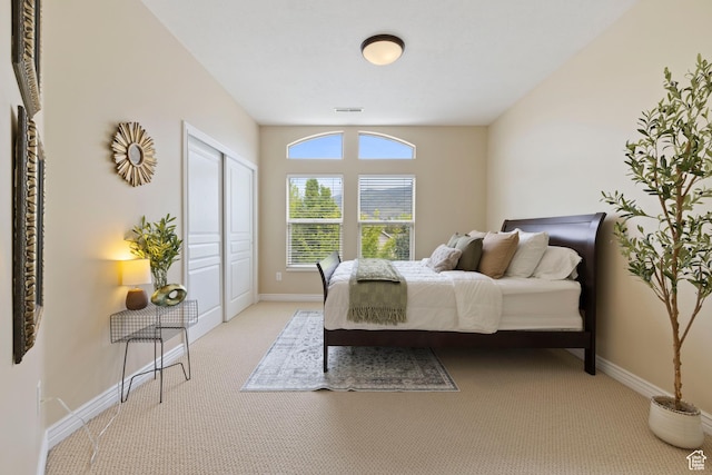 bedroom featuring light colored carpet, baseboards, a closet, and visible vents