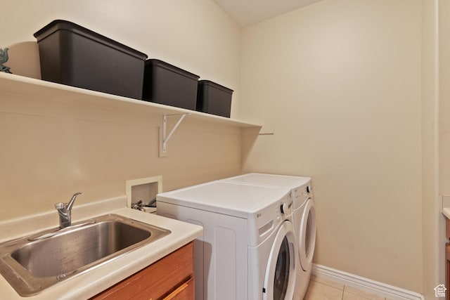 washroom featuring a sink, cabinet space, independent washer and dryer, light tile patterned floors, and baseboards