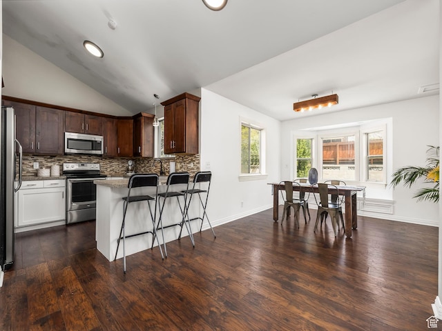 7123 S Watermill Way, Cottonwood Heights, UT 84121 - kitchen with a kitchen breakfast bar, backsplash, appliances with stainless steel finishes, a peninsula, and lofted ceiling