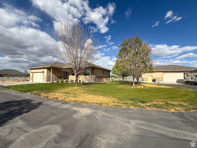 view of front of property featuring stucco siding, aphalt driveway, a front yard, and a garage