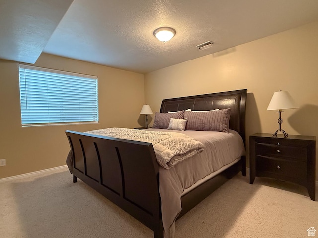 bedroom with light colored carpet, baseboards, visible vents, and a textured ceiling
