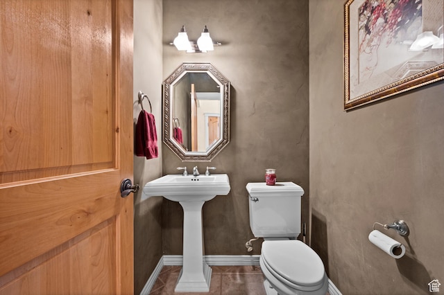 bathroom featuring baseboards, tile patterned flooring, and toilet