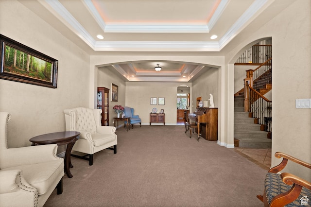 living area featuring ornamental molding, stairs, carpet flooring, a tray ceiling, and arched walkways