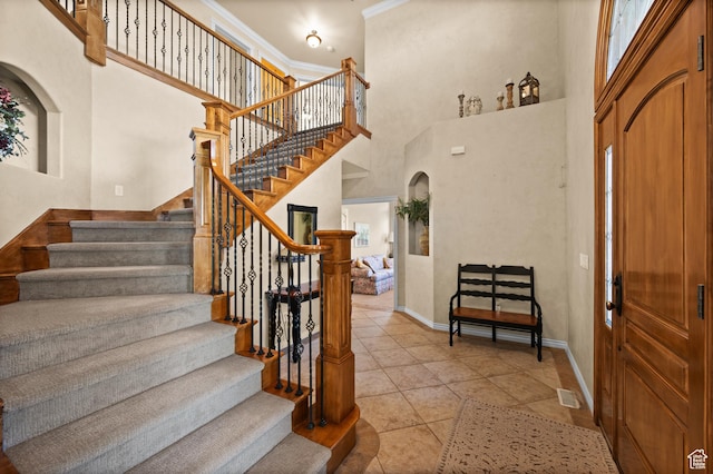 interior space featuring tile patterned flooring, ornamental molding, baseboards, and a towering ceiling