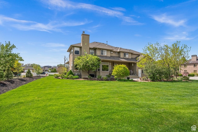 back of property featuring a lawn, stucco siding, and a chimney