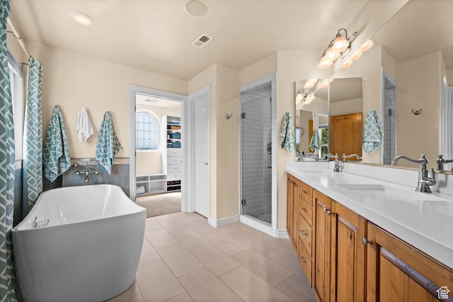 bathroom with double vanity, visible vents, a freestanding bath, a stall shower, and a sink