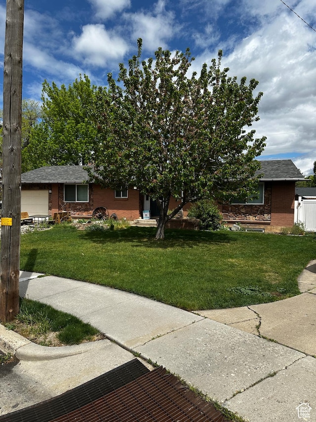 view of front of house with brick siding, a shingled roof, and a front lawn