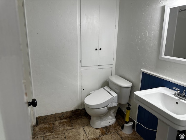 5160 S 200 E, Washington Terrace, UT 84405 - bathroom featuring stone tile floors, a textured wall, toilet, a sink, and a wainscoted wall