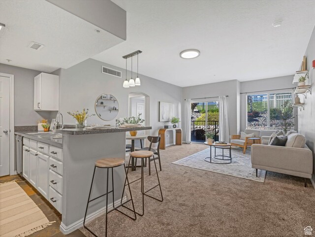 165 W Albion Village Way Unit 103, Sandy, UT 84070 - kitchen with white cabinets, open floor plan, visible vents, and a breakfast bar