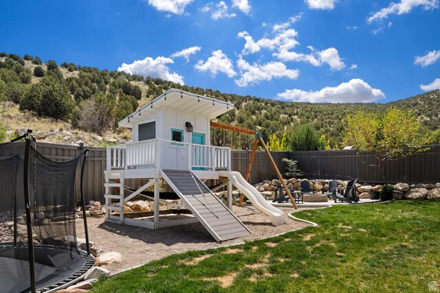 4126 E Cherokee, Eagle Mountain, UT 84005 - view of playground with a trampoline, a lawn, a view of trees, a fenced backyard, and a fire pit