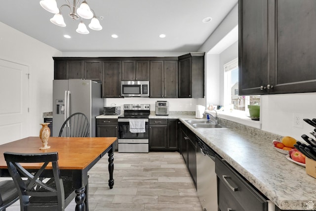 kitchen with an inviting chandelier, a sink, appliances with stainless steel finishes, and light countertops