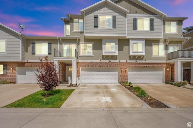 view of property featuring stucco siding, brick siding, board and batten siding, an attached garage, and driveway