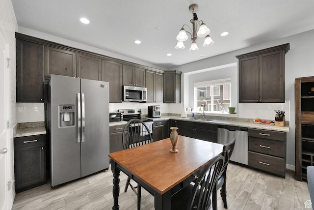 kitchen featuring a sink, appliances with stainless steel finishes, dark brown cabinetry, and light wood-style flooring