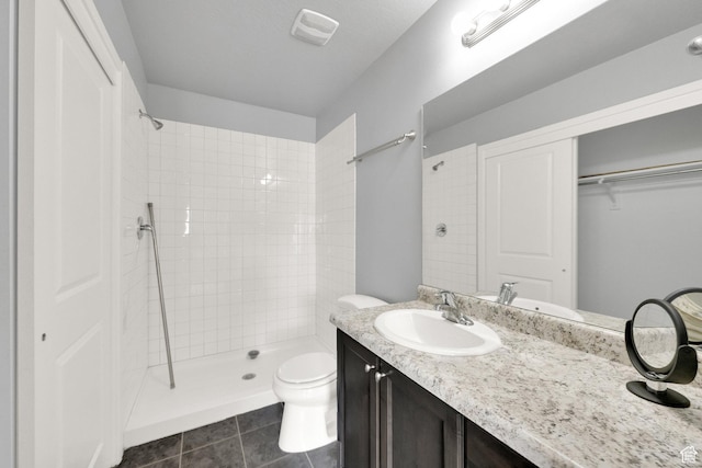 full bath with vanity, tile patterned flooring, a tile shower, and toilet