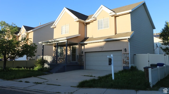 view of front facade with an attached garage, fence, stone siding, and stucco siding