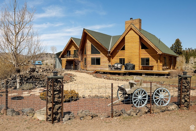 rear view of property featuring a chimney, log siding, fence private yard, and a wooden deck
