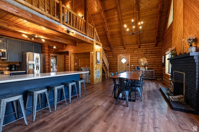 dining space featuring wood ceiling, a towering ceiling, stairway, beamed ceiling, and dark wood-style floors
