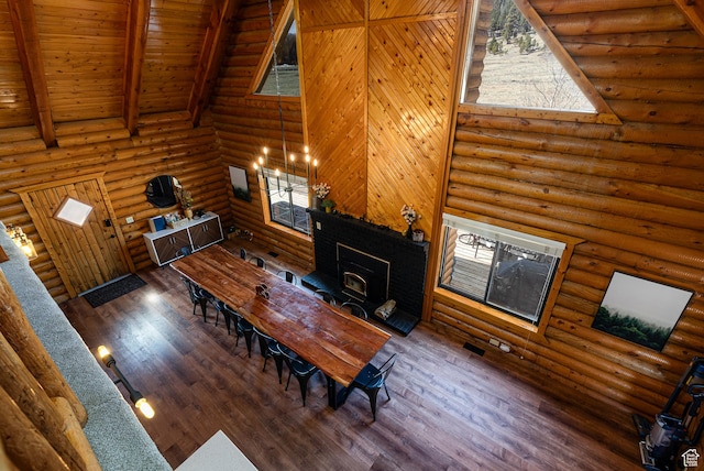 dining area with wood ceiling, a wood stove, beam ceiling, wood finished floors, and high vaulted ceiling