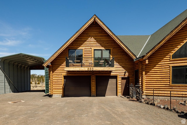 log home with a carport, a balcony, driveway, and log siding