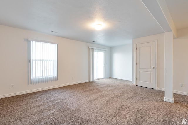 carpeted spare room featuring baseboards and visible vents