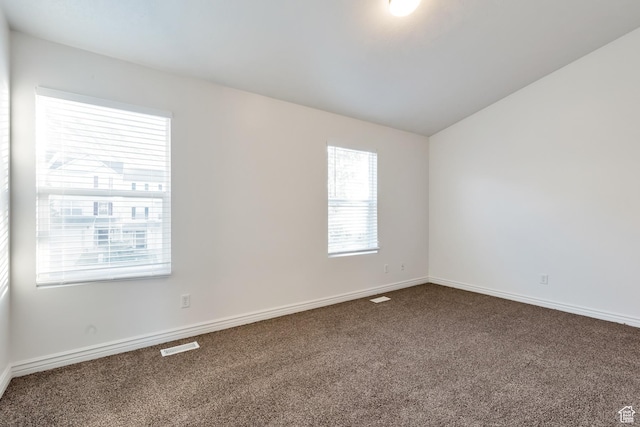spare room featuring carpet flooring, baseboards, visible vents, and vaulted ceiling