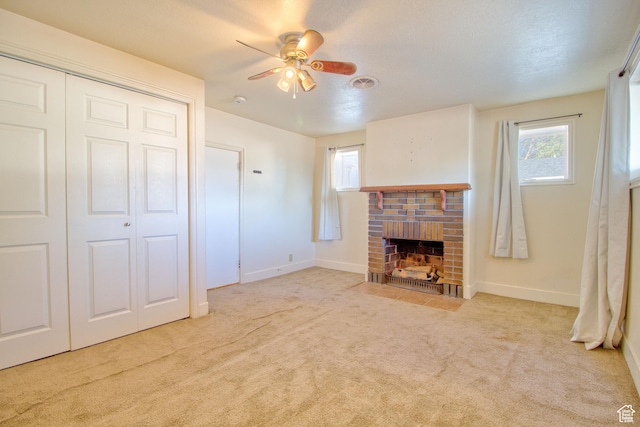 unfurnished living room featuring carpet floors, ceiling fan, a fireplace, and baseboards