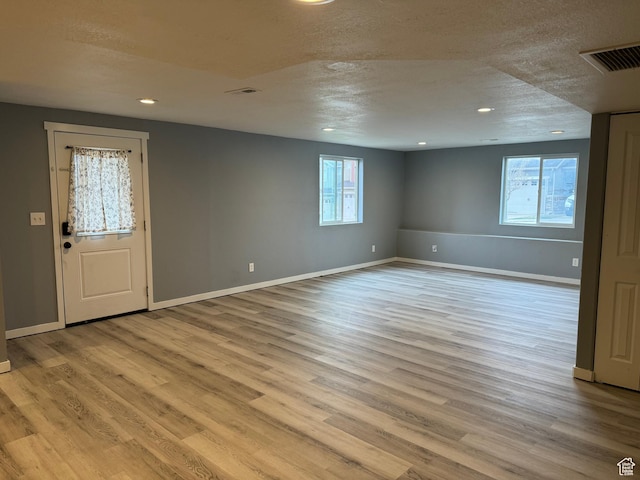 interior space featuring baseboards, recessed lighting, a textured ceiling, and wood finished floors
