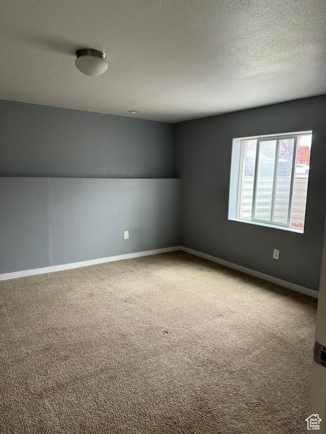 empty room featuring carpet flooring, a textured ceiling, and baseboards